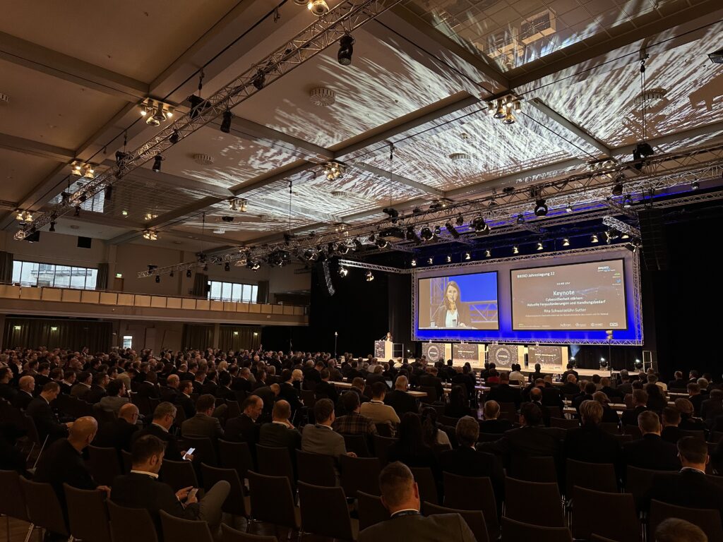 Fotot: Foto des Plenums und eines Screens zum Thema Glasfasermakrt: Status Quo im Rahmen einer Diskussion zum Thema Umsetzung der Gigabitstrategie des Bundes bei der BREKO Jahrestagung 2022